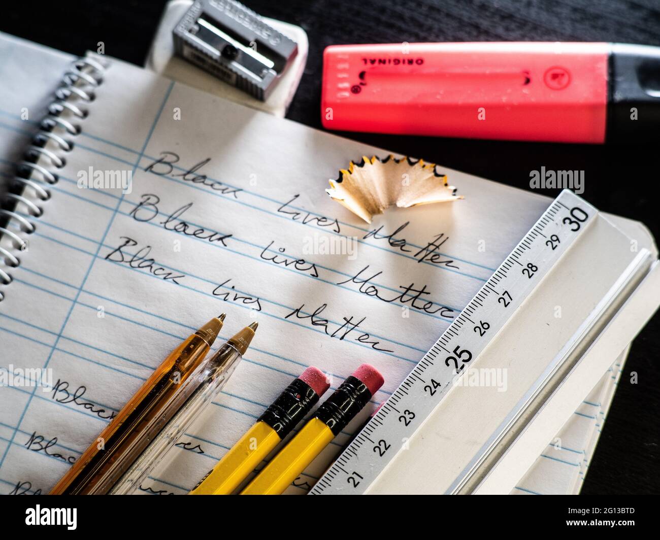 Black Lives Matter slogan written on a school calligraphy notebook, next to him rubber, pencil, pencil sharpener, pen and marker Stock Photo