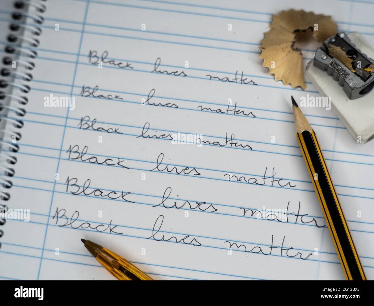 A calligraphic school notebook with pencil, rubber, pencil sharpener and pens show the slogan Black LIves Matter. Stock Photo