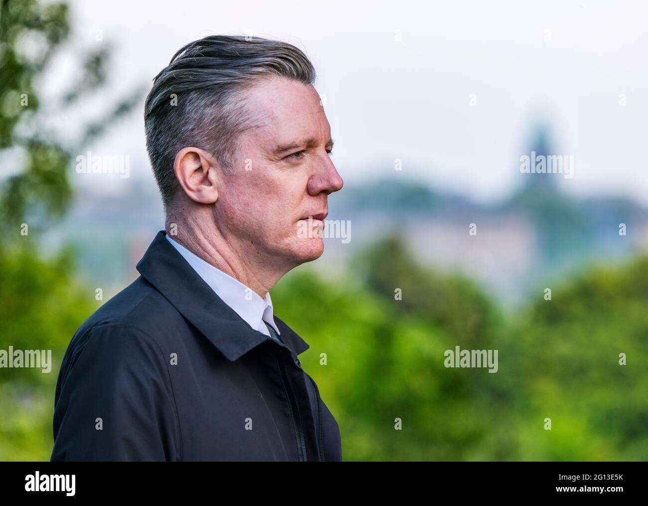 Close up of Fergus Linehan, Festival Director, at Edinburgh International Festival launch, Royal Botanic Garden with city skyline, Scotland, UK Stock Photo