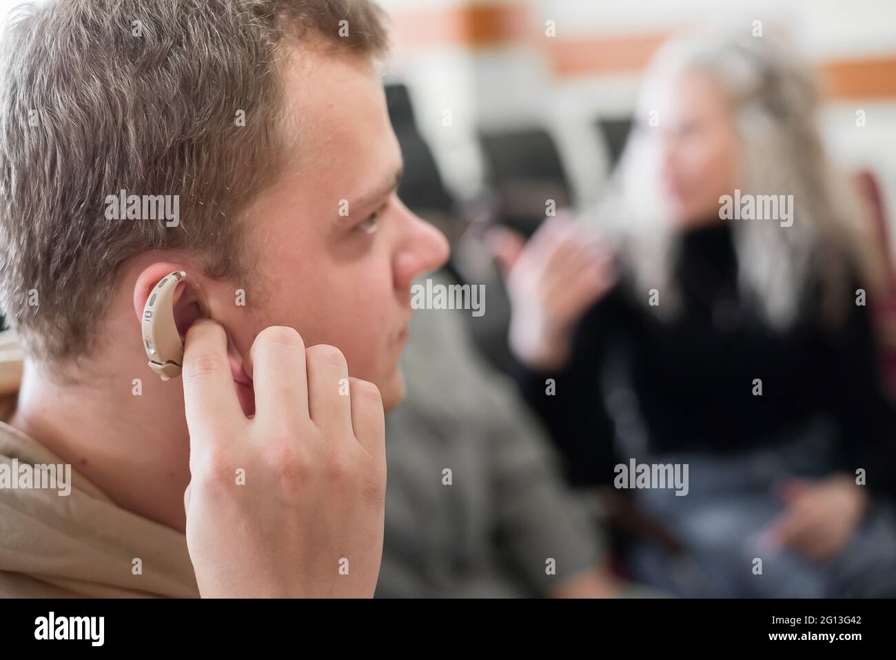 A young man puts on a hearing aid. Portable sound amplifier for the