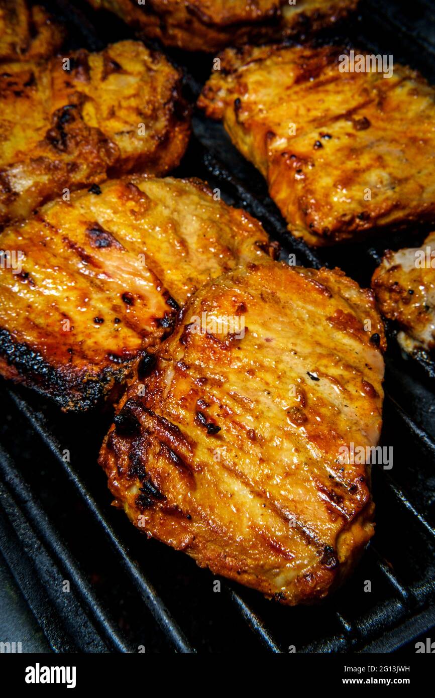 Marinated honey glaze pork chops cooking on propane grill Stock Photo