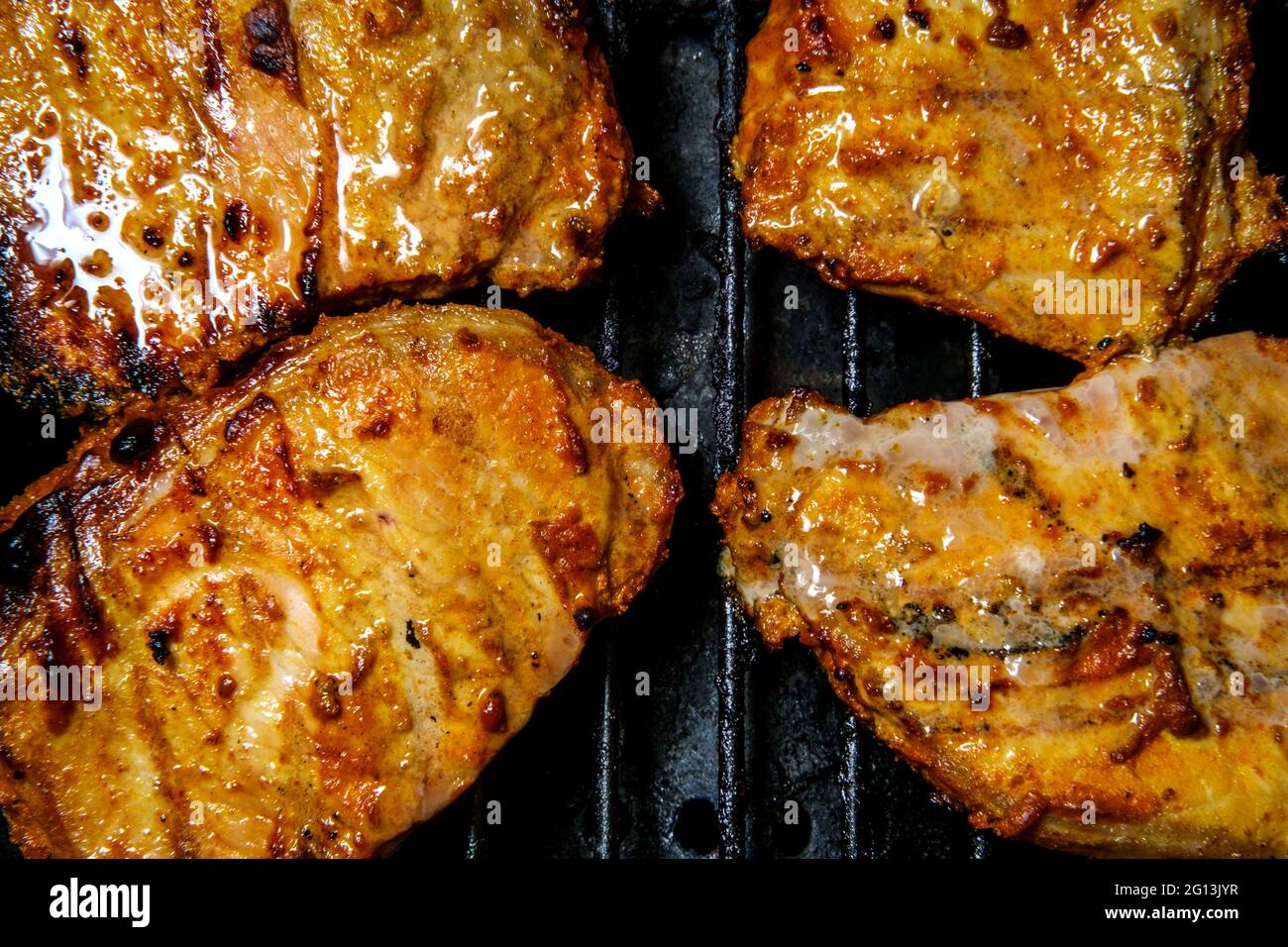Marinated honey glaze pork chops cooking on propane grill Stock Photo