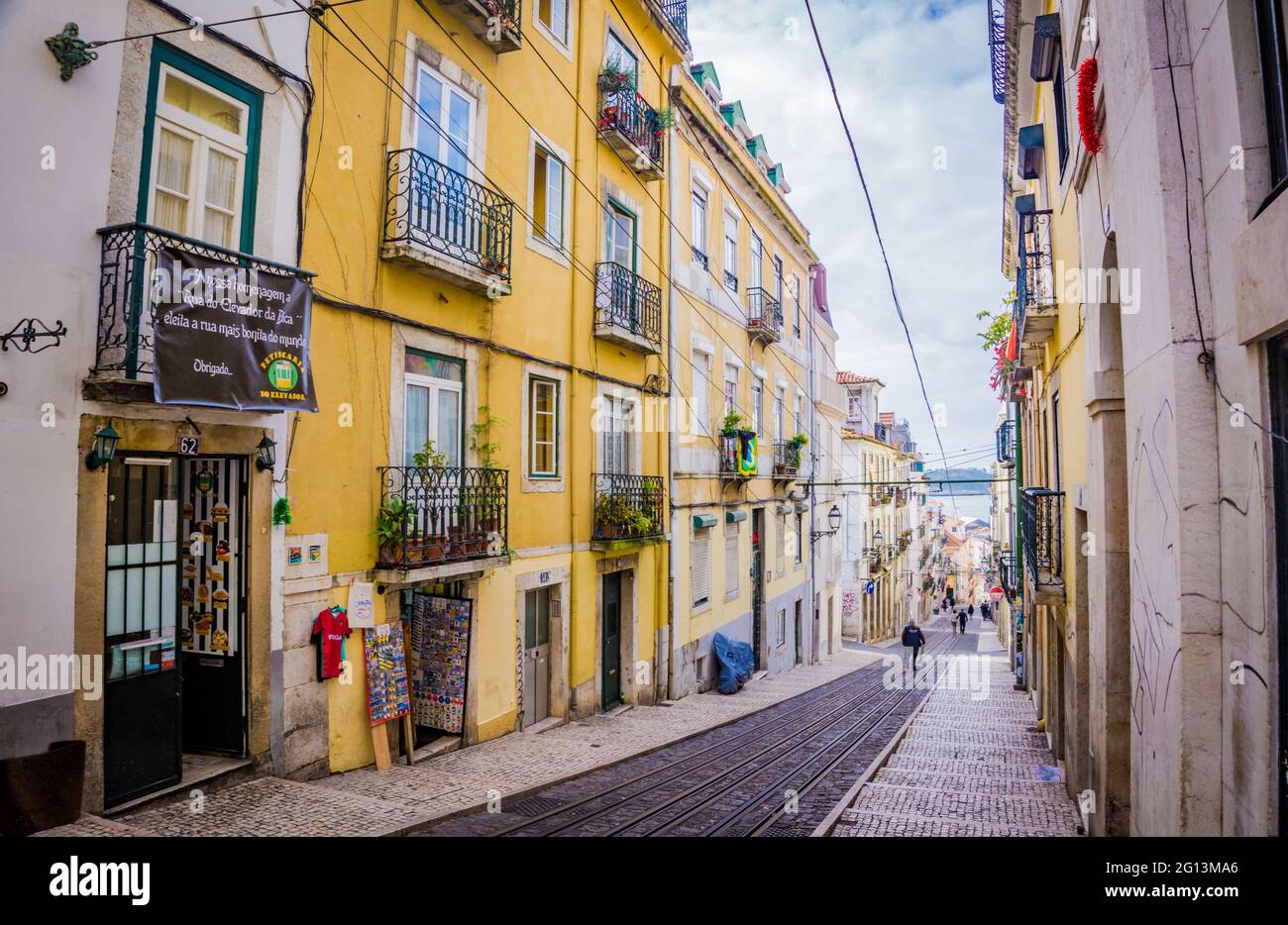 Streets of the city center of Lisbon with funicular rails. Souvenir shops, old vintage buildings with balconies, restaurants. Portugal Stock Photo