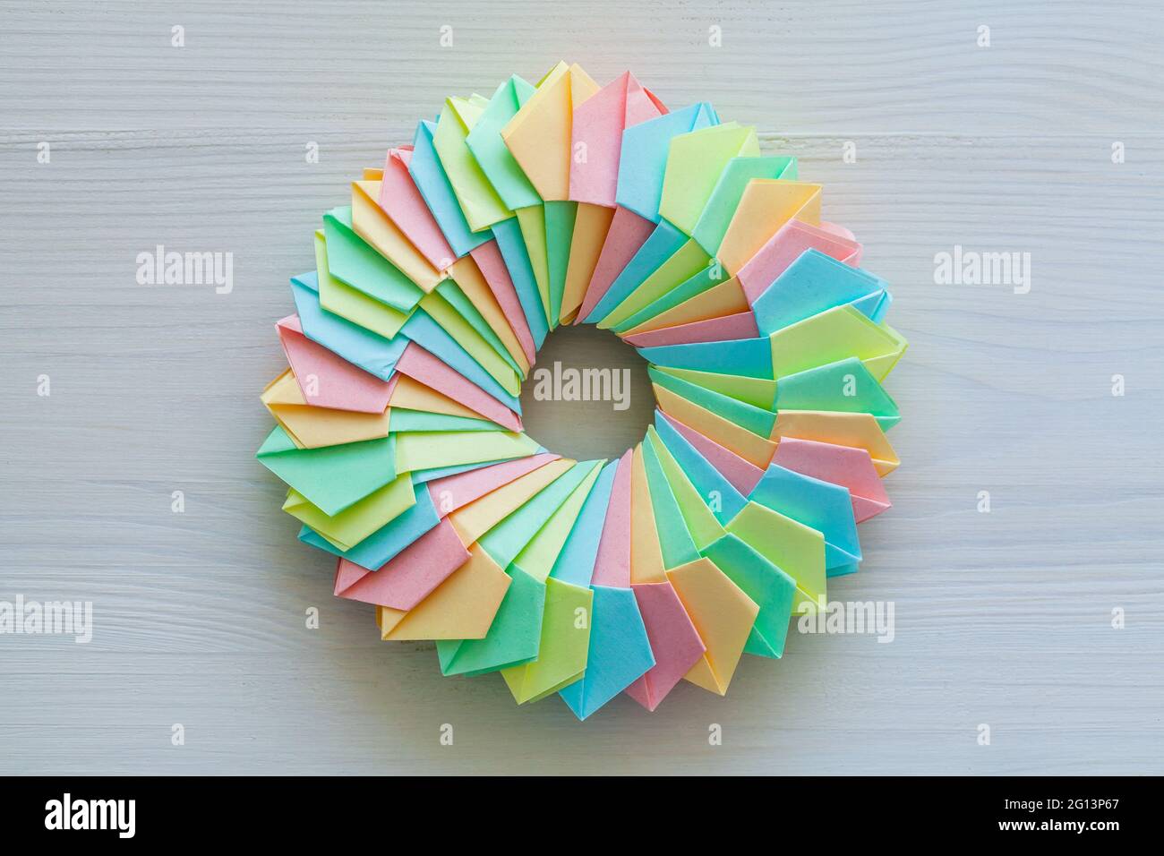 Origami, abstract parametric ring structure made of colorful paper sheets lay on a white desk, top view Stock Photo