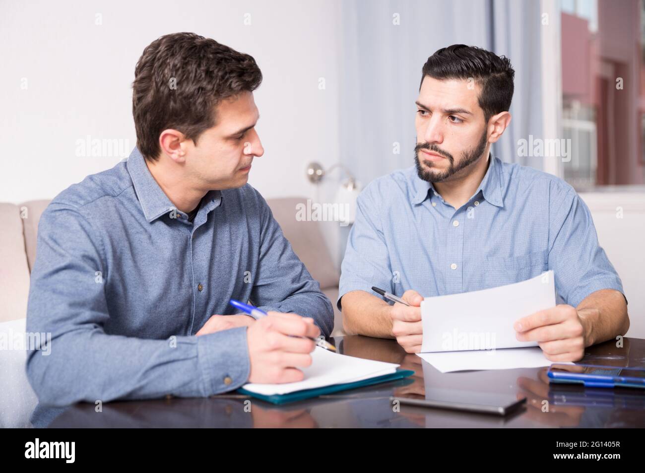 Two serious males with documents at table Stock Photo