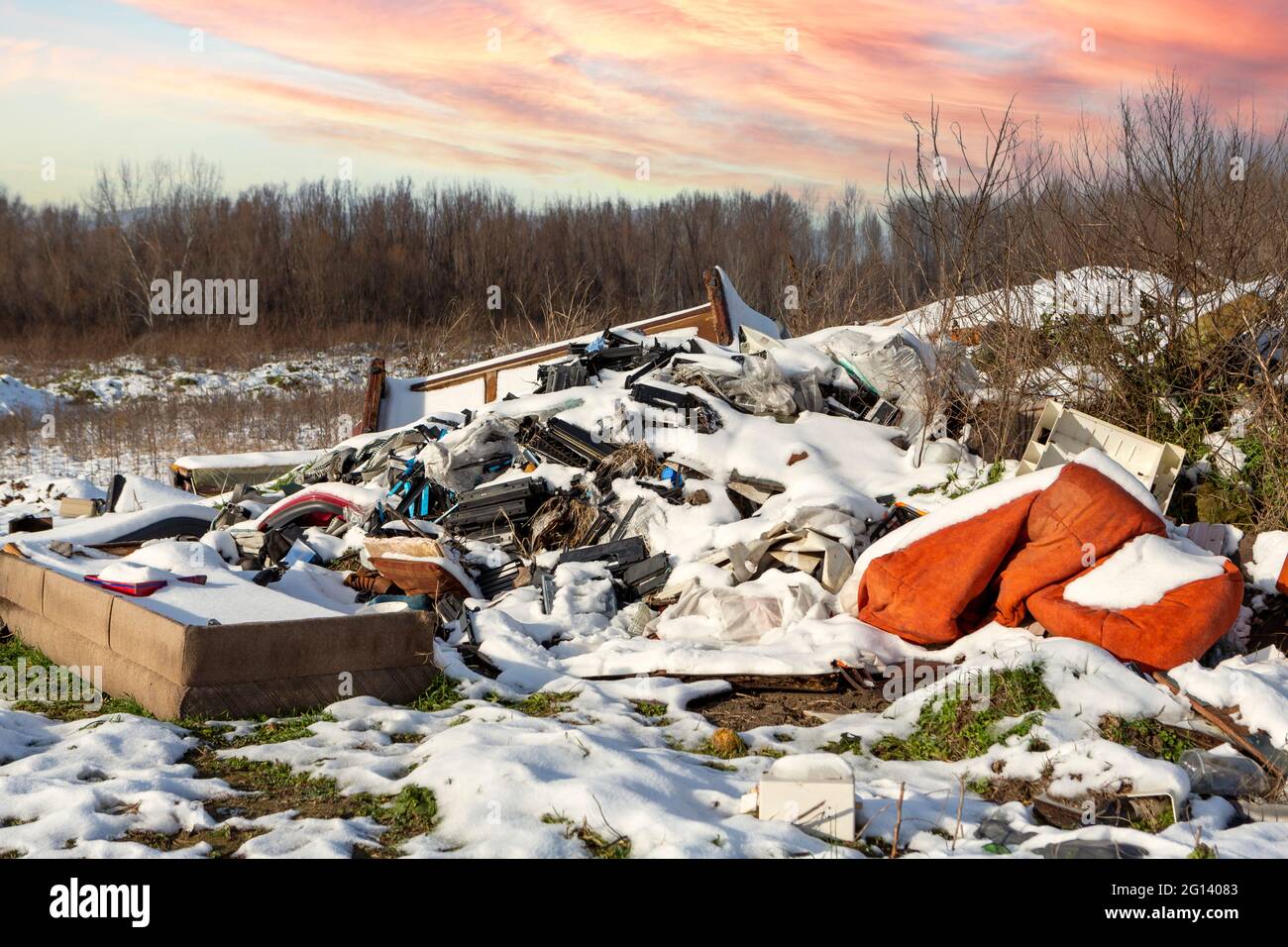 Ecological crisis. Different garbage and trash on snow at beautiful winter forest at colorful sky. Environmental pollution by garbage. Destructive hum Stock Photo