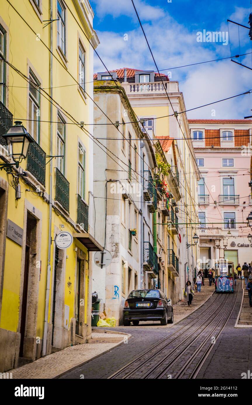 LISBON, PORTUGAL - MARCH 25, 2017: Old beautiful touristic street of Lisbon with old colourful buildings, funicular and rails. Stock Photo