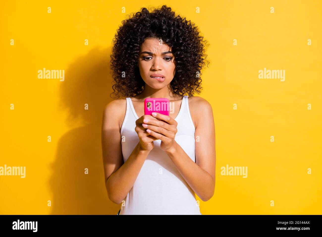 Photo of cute guilty young dark skin lady wear white singlet communicating modern device isolated yellow color background Stock Photo