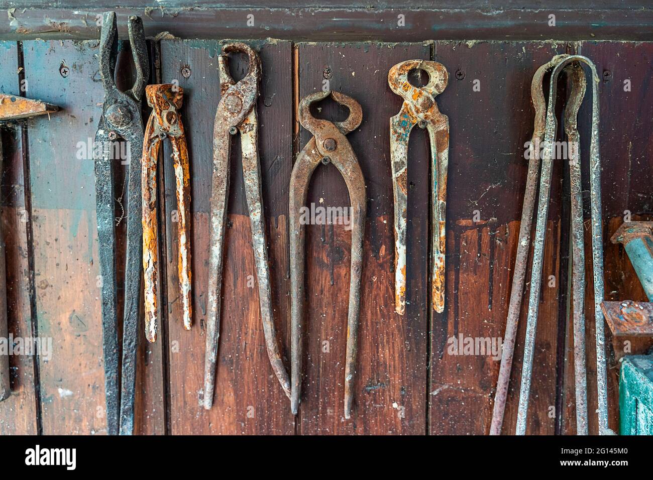 rusty blacksmith tools hanging on a wooden board Stock Photo