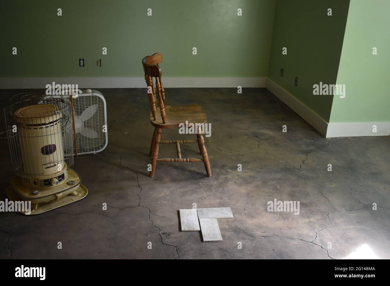 A chair, radiator, and old fan in the middle of an empty abandoned ...