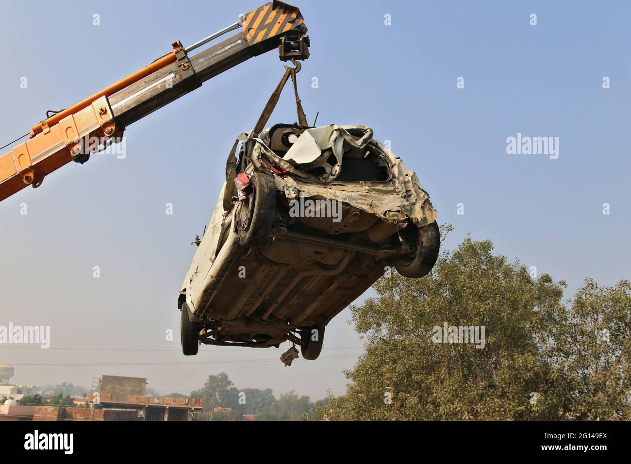 A crane lifts a broken car for loading onto a tow truck at the scene of the accident. Haryana, India Stock Photo