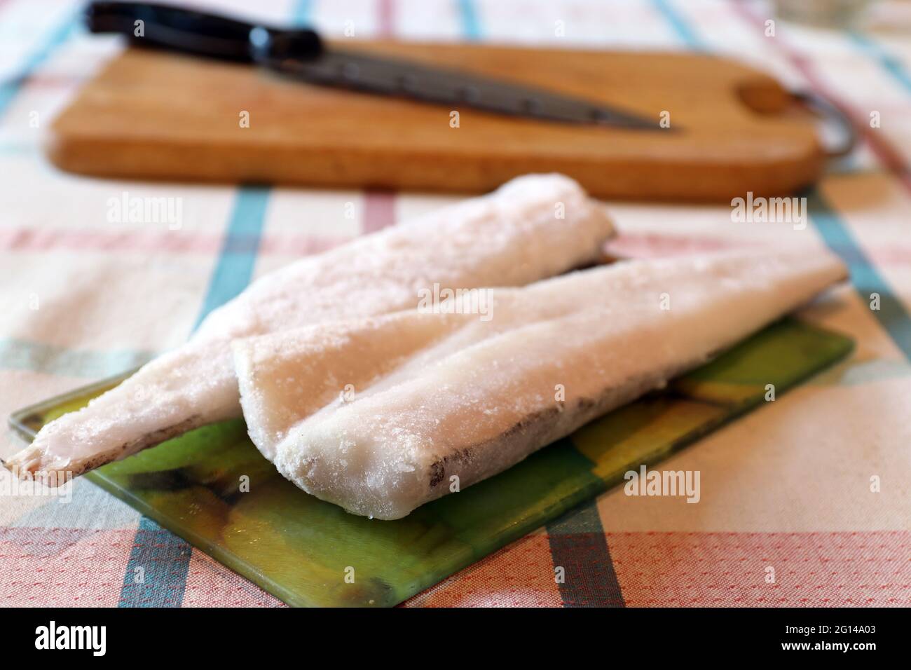 Several slices of frozen fish on glass cutting board Stock Photo