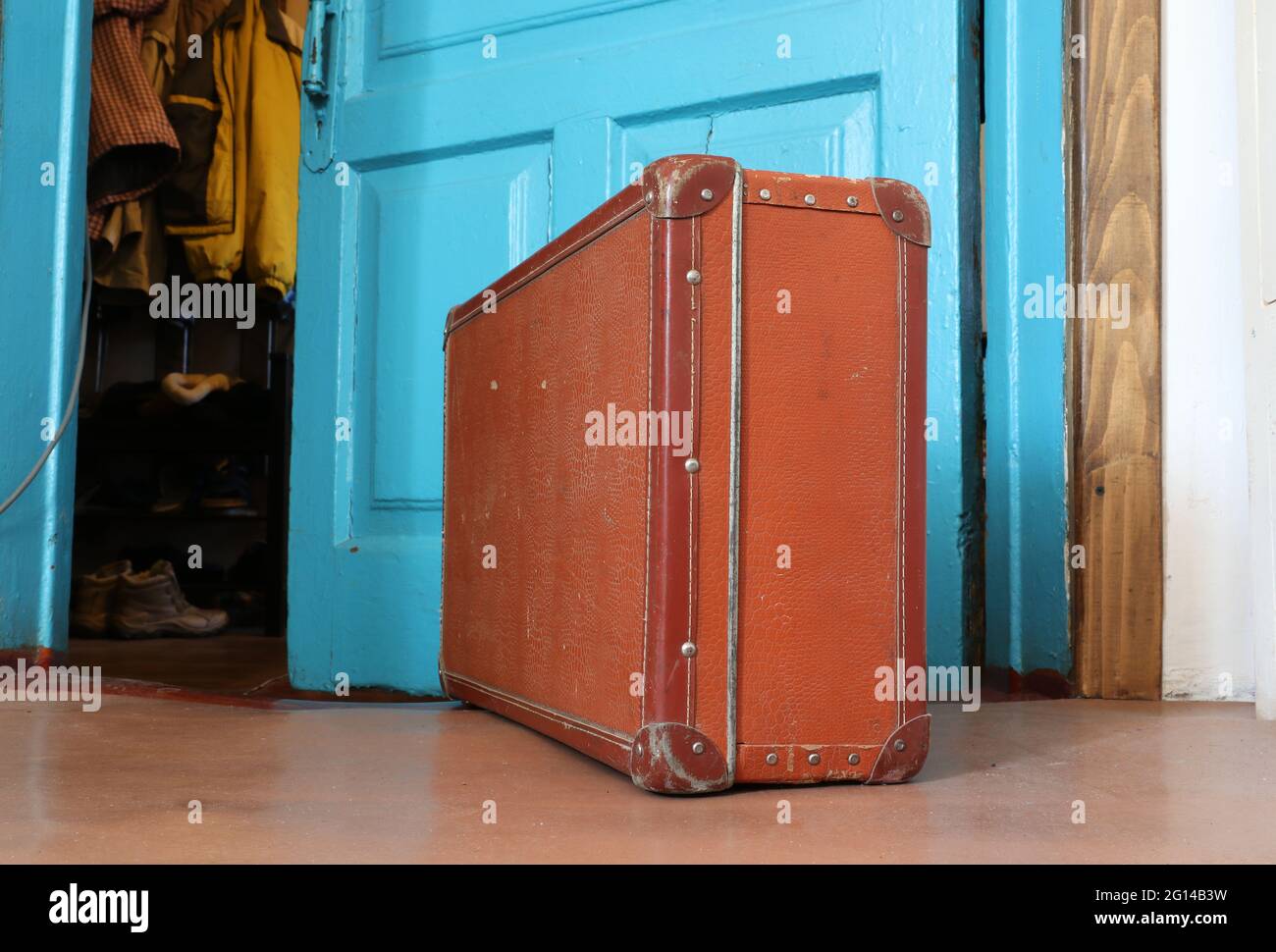 Vintage old brown suitcase in front of an open door Stock Photo
