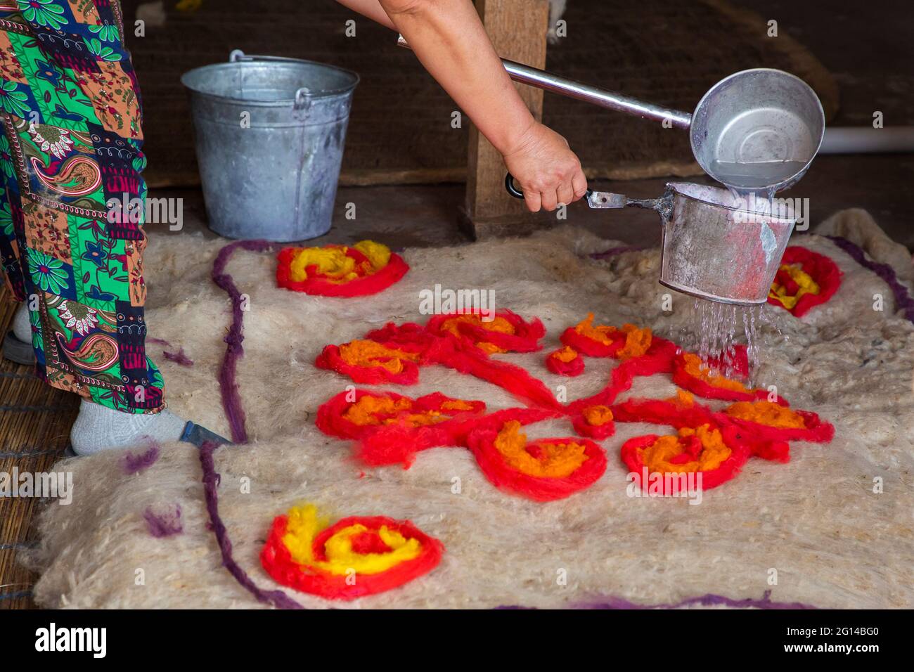 Making felt traditional way by putting hot water to sit the pattern on the felt carpet. Stock Photo