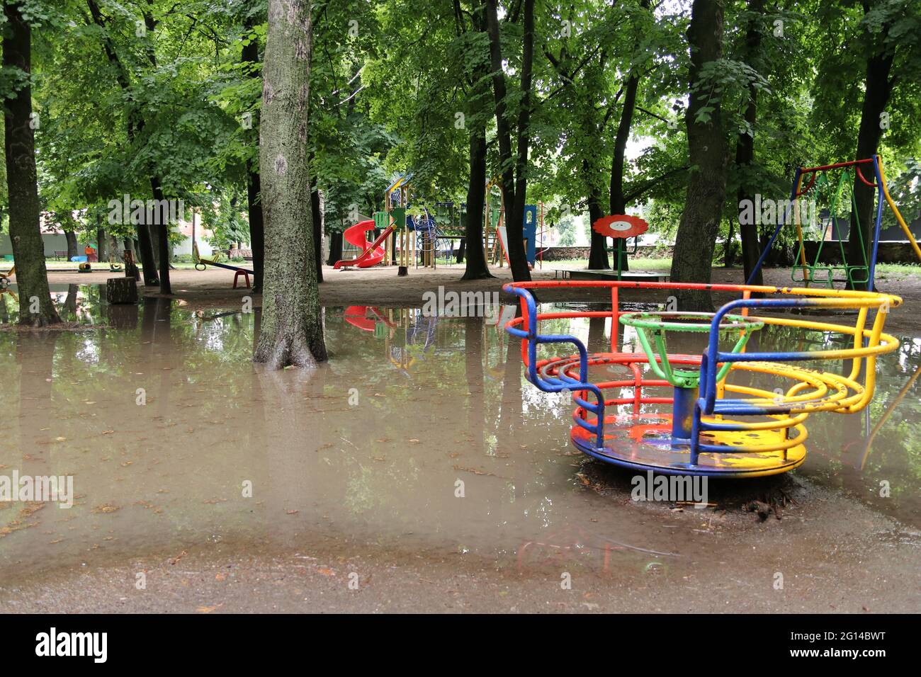 Colorful playground in the park after strong rain. Playground is flooded with water. Stock Photo
