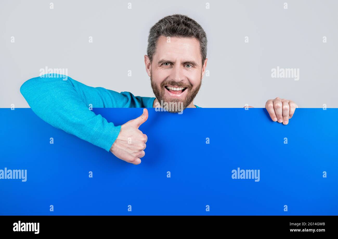 product presenting. presenting novelty information. male behind blue paper show thumb up. Stock Photo