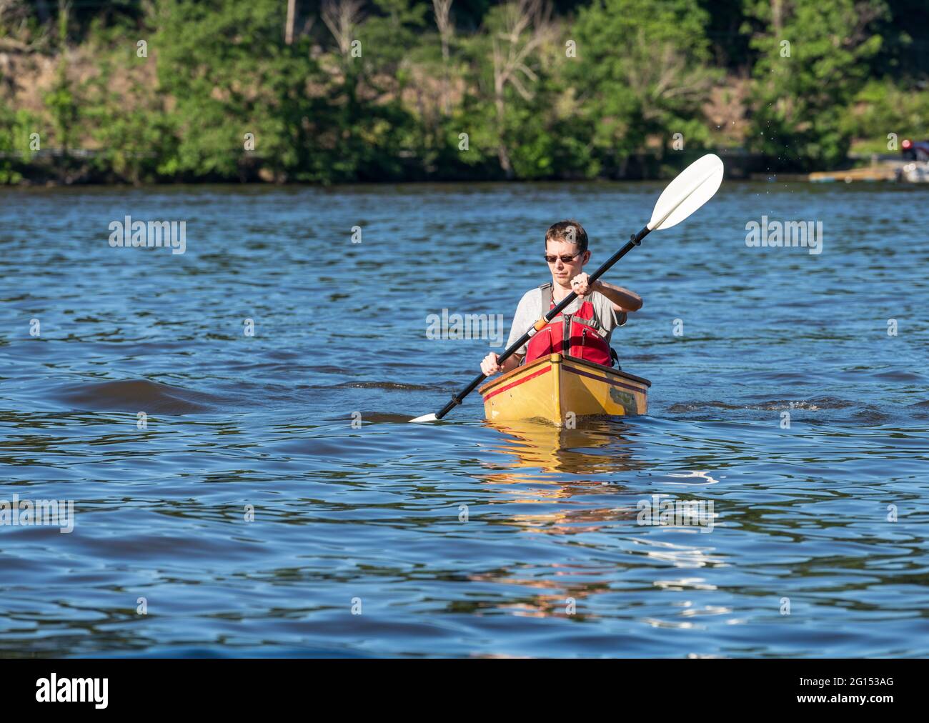 Young man in lifejacket paddling a pack canoe using a kayak paddle on a