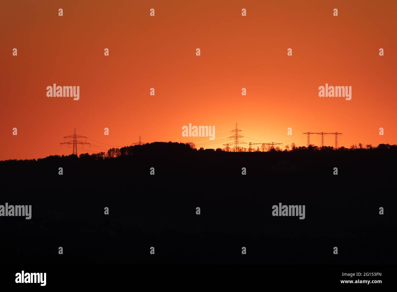 silhouette of high voltage power lines and pylons against a beautiful ...