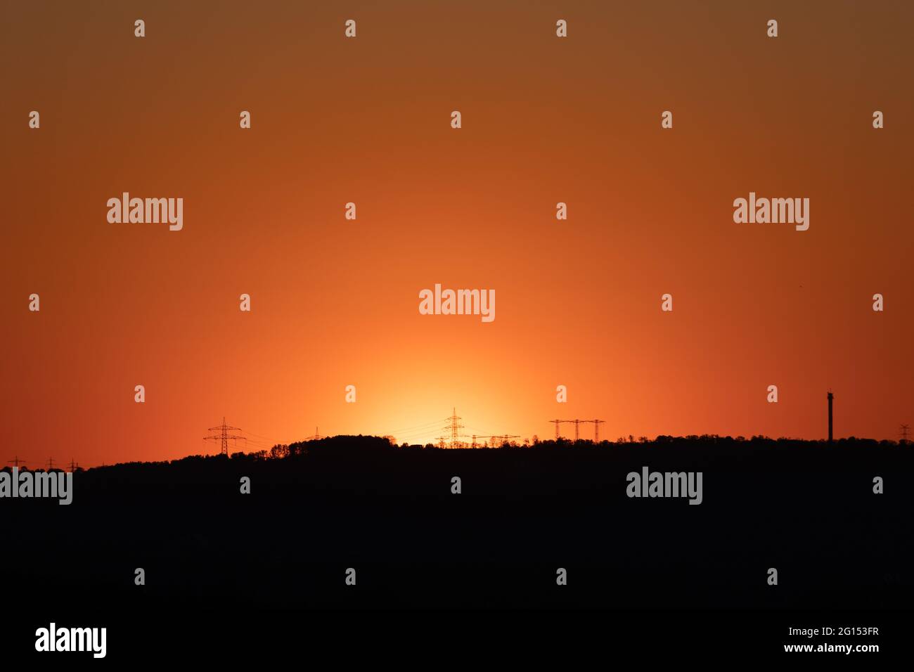 silhouette of high voltage power lines and pylons against a beautiful ...