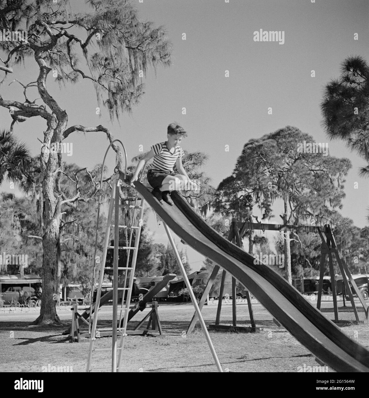 Boy on Playground Slide, Sarasota Trailer Park, Sarasota, Florida, USA, Marion Post Wolcott, U.S. Farm Security Administration, January 1941 Stock Photo