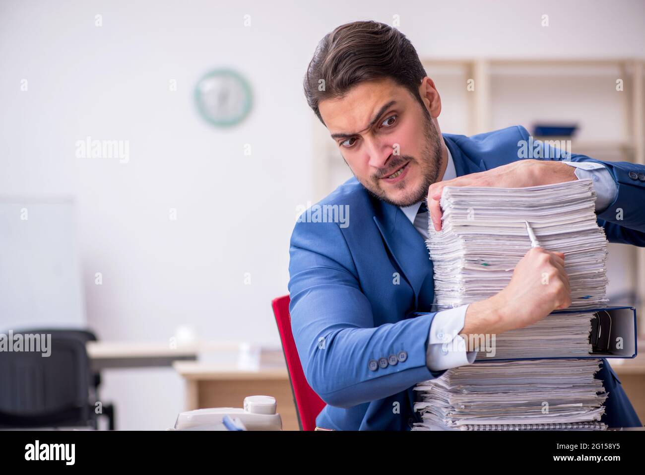 Young male employee and too much work in the office Stock Photo - Alamy
