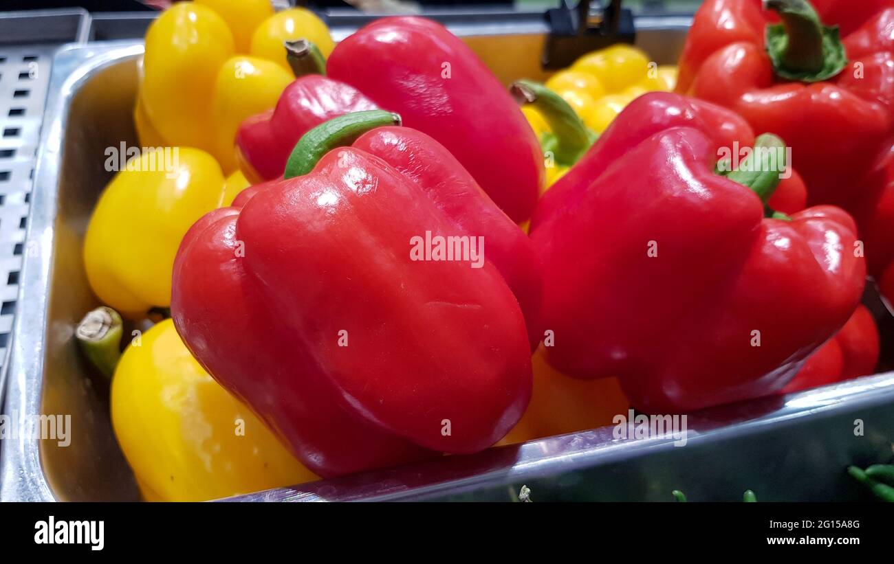 Red and yellow bell peppers are placed in trays for sale in the market ...