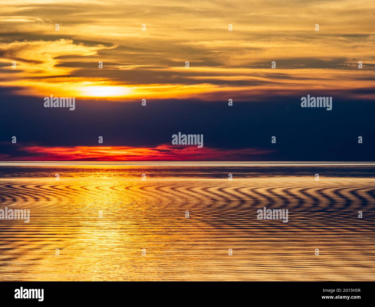 Image of a setting sun casting a warm yellow glow with dark clouds over ...