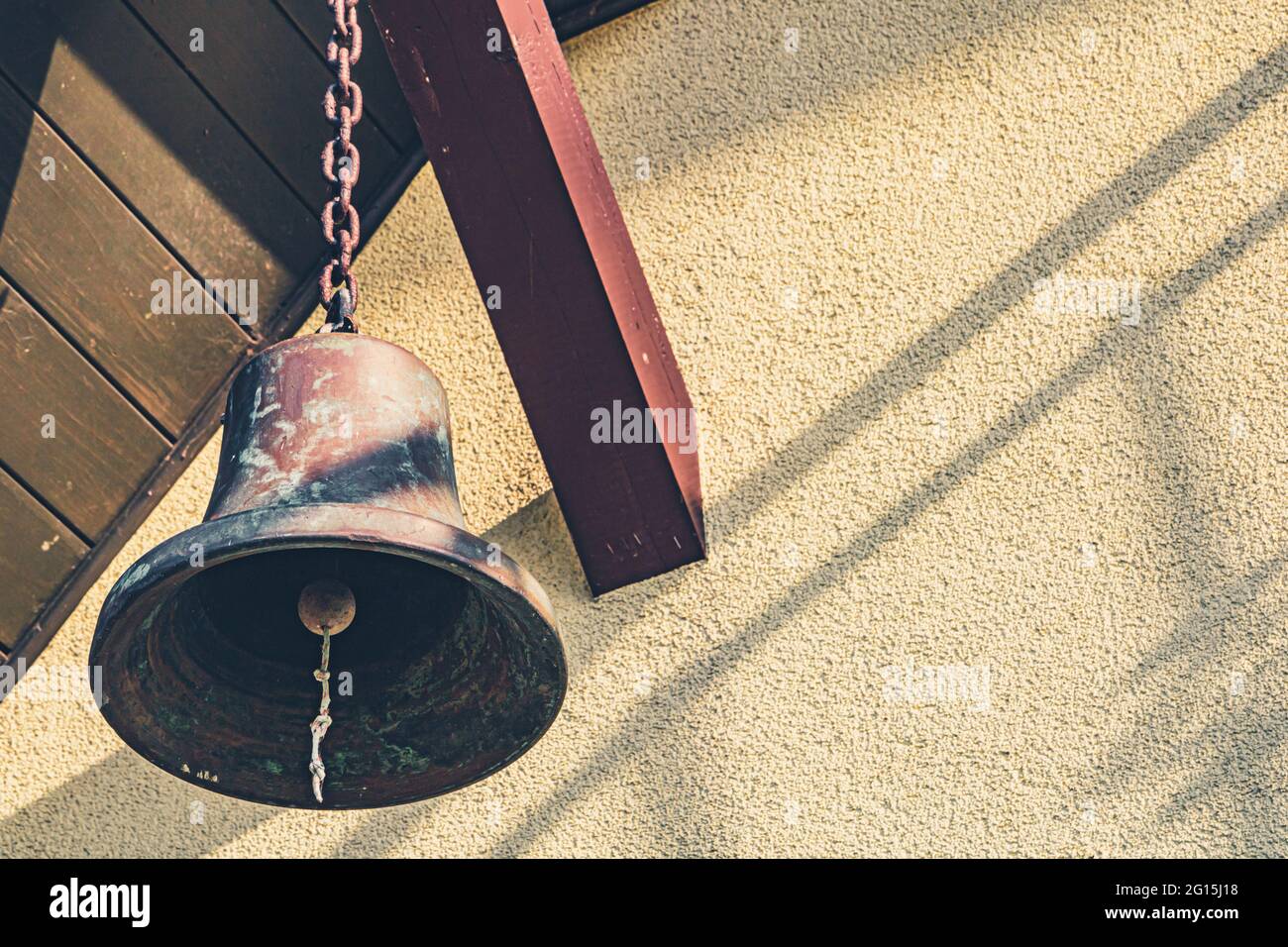 Große, alte Schiffsglocke hängt an einem Holzbalken als Dekoration - Glocke als Deko an einer Kette Stock Photo