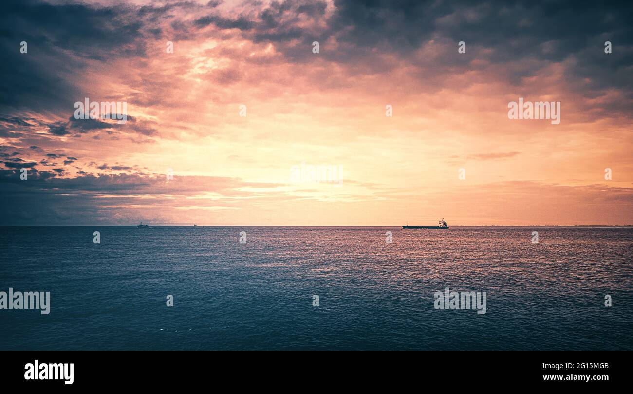 Cuxhafen Containerhafen an der Nordsee mit großem Tanker und Schiffscontainer bei spektakulärer Aussicht und dramatischem Himmel und Wolkenband. Stock Photo