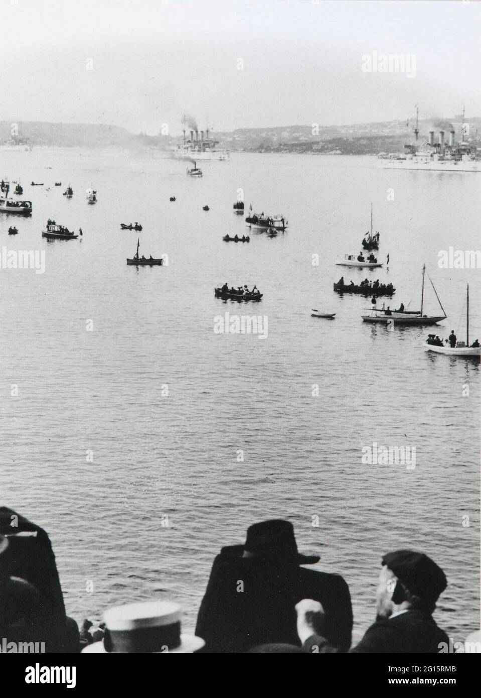 THE 1908 AMERICAN FLEET IN SYDNEY HARBOUR *** Local Caption *** PHOTOGRAPH  THE 1908 AMERICAN FLEET IN SYDNEY HARBOUR  Photograph.  Untitled (the 1908 american fleet to sydney harbour).  Sydney, australia, 1908.  Silver gelatin print, paper.  The black and white image depicts the Great White Fleet in sydney harbour steaming past crowds of spectators.  The fleet appears at upper c. People watch the fleet from small craft, longboats and skiffs, at c.  The heads of several people appear at l.L. Corner and bot. C. Perhaps watching the fleet from a ship. Stock Photo