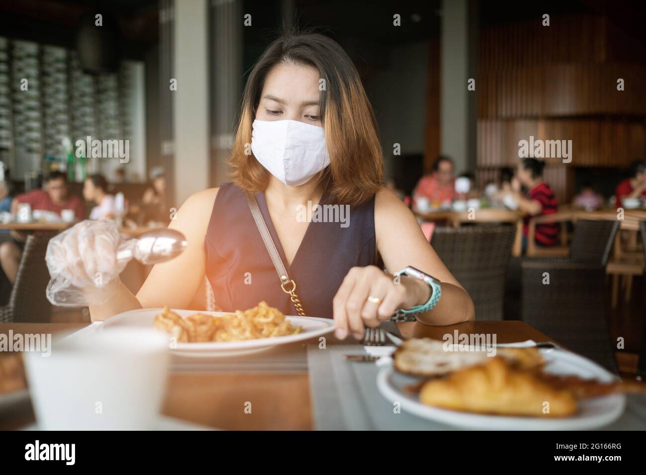 A woman wearing a mask eats food Stock Photo Alamy