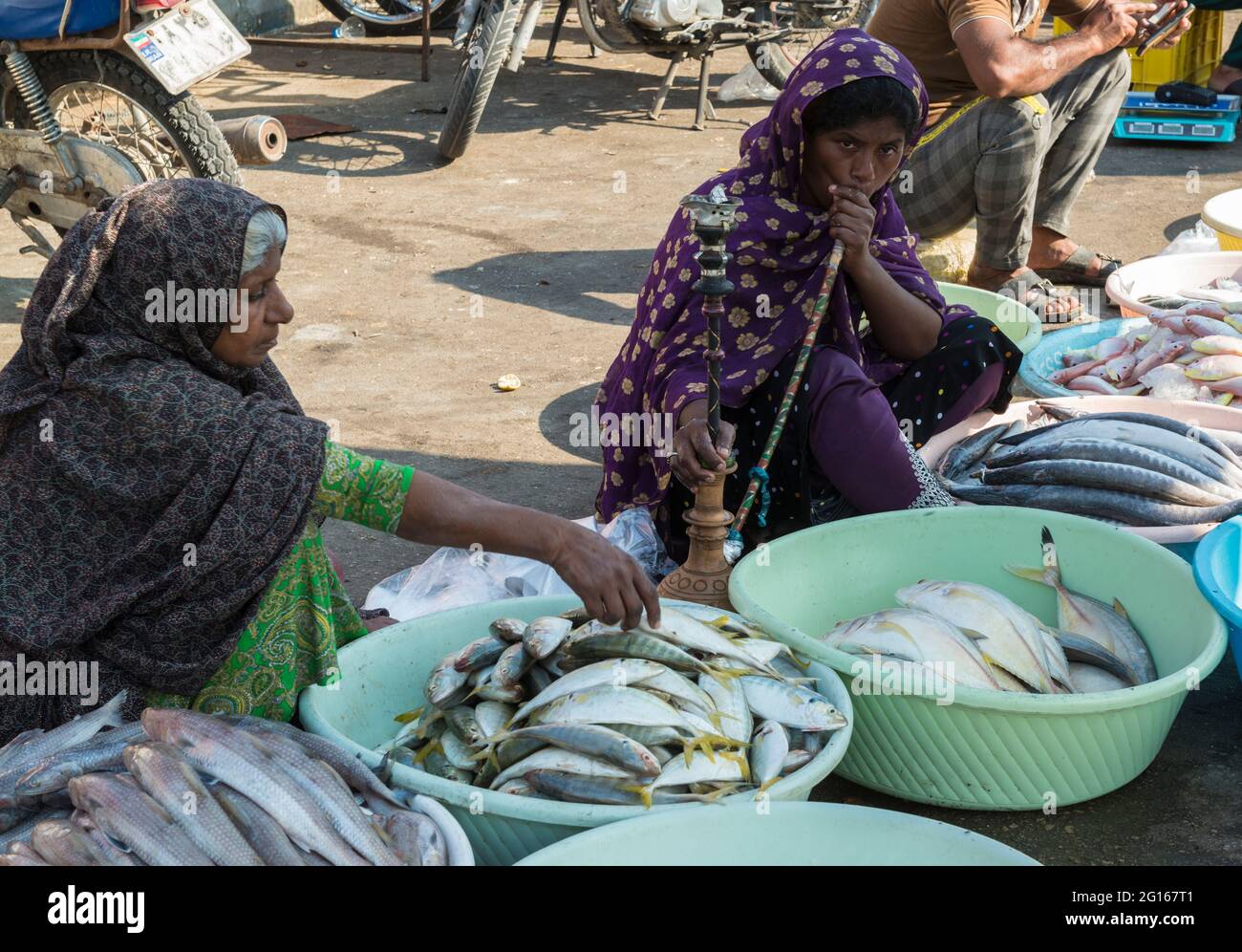 Bandari women, the right woman smoking a hookah, selling fish on the market.Bandar Abbas, Hormozgān Province, Iran Stock Photo