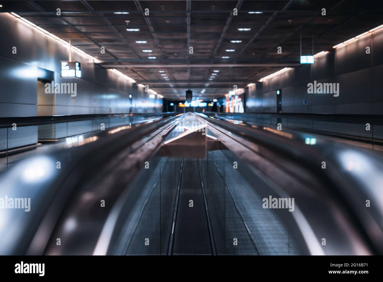 View with a shallow depth of field of two travelators in a modern airport area with a selective focus in the middle; two moving walkways in a dark con Stock Photo