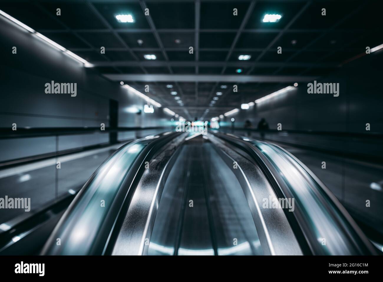 View with a shallow depth of field of two travelators in a contemporary airport with selective focus in the foreground; two moving walkways in a dark Stock Photo
