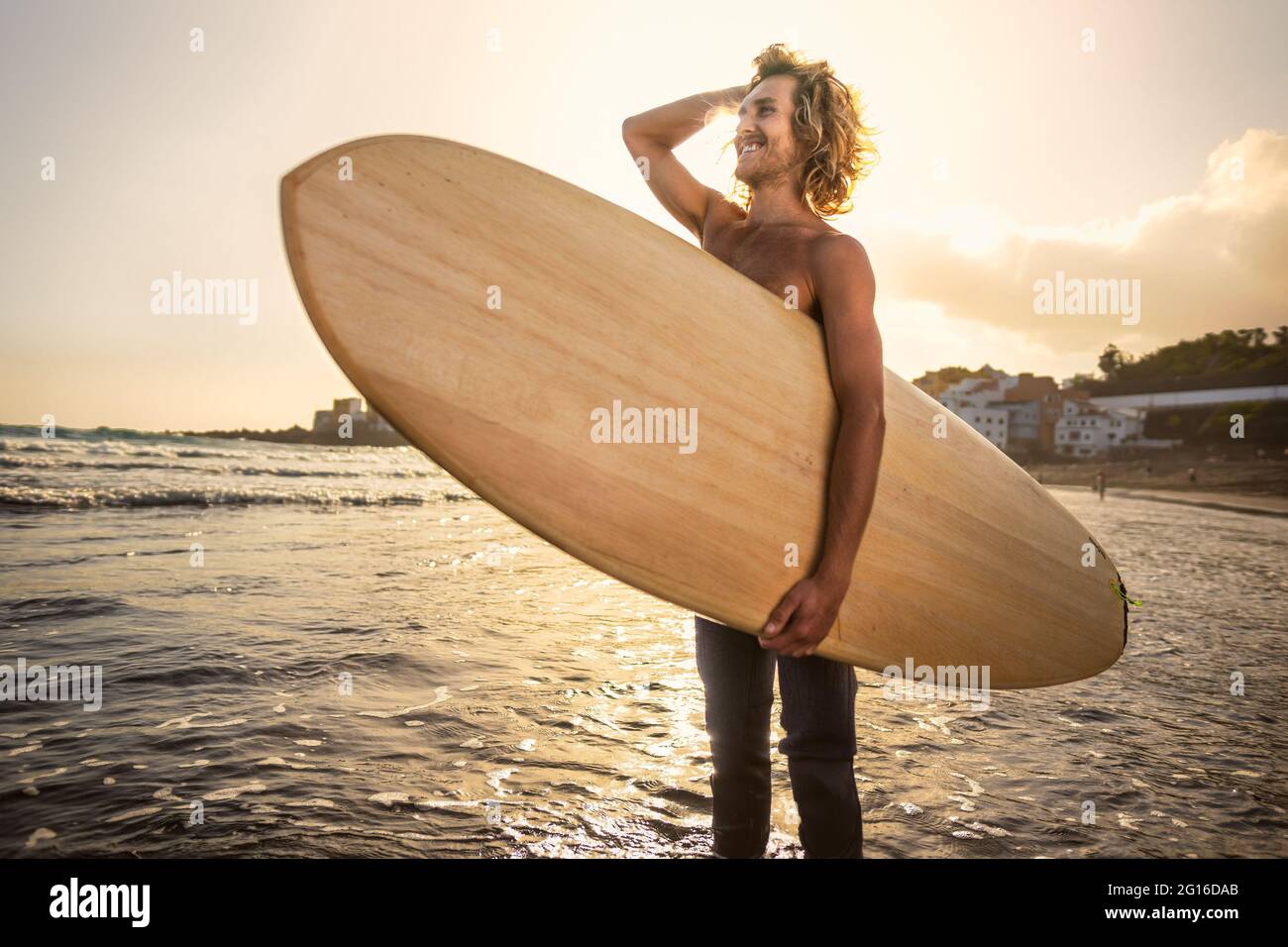 Young surfer having fun enjoying a surf day at sunset time - Extreme sport lifestyle people concept Stock Photo