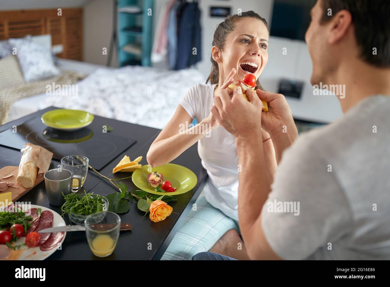 A young couple having a good time feeding each other while having a breakfast in a cheerful atmosphere at home. Love, together, breakfast, home Stock Photo