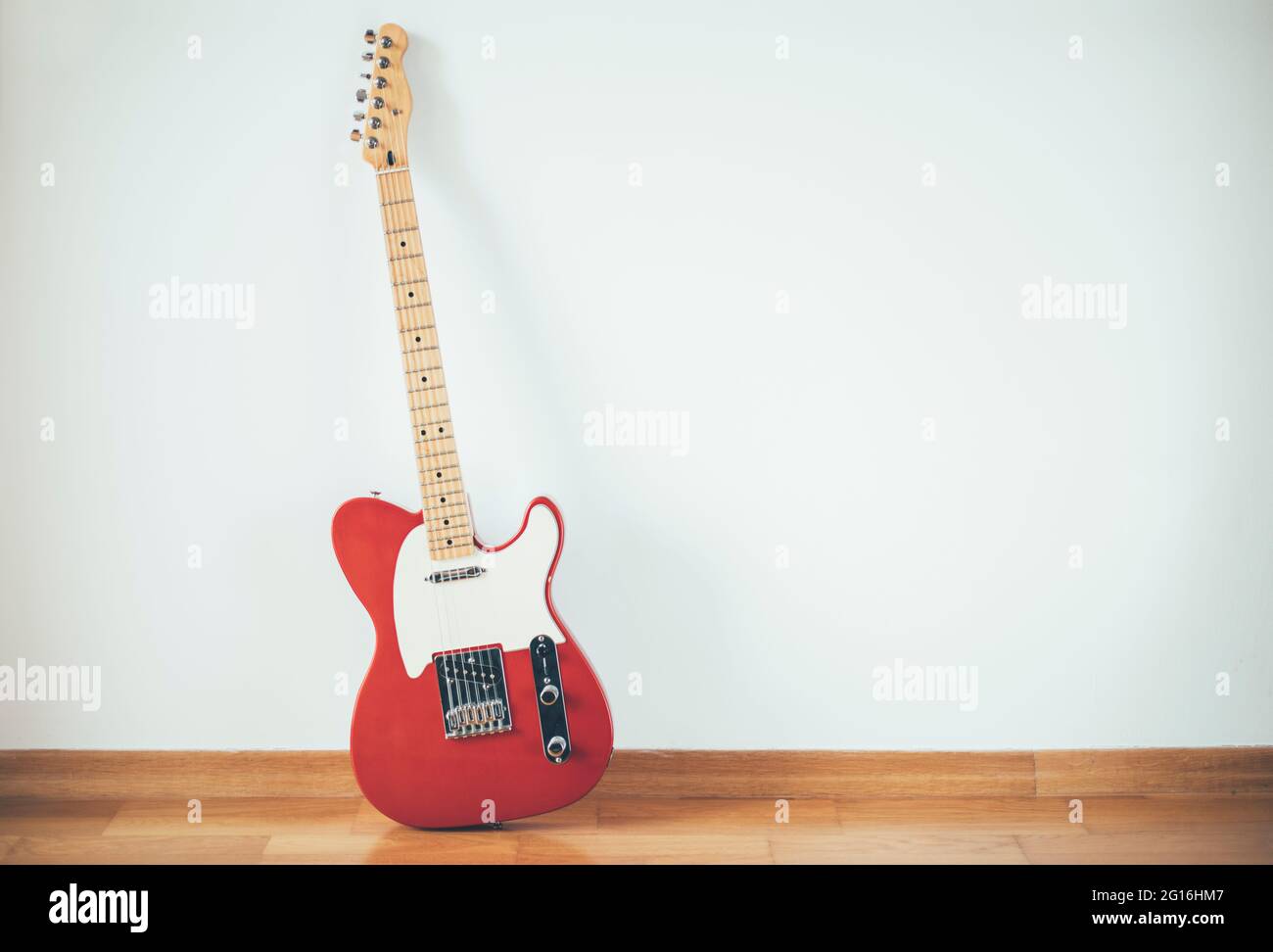 Red electric guitar on white wall background, copy space Stock Photo