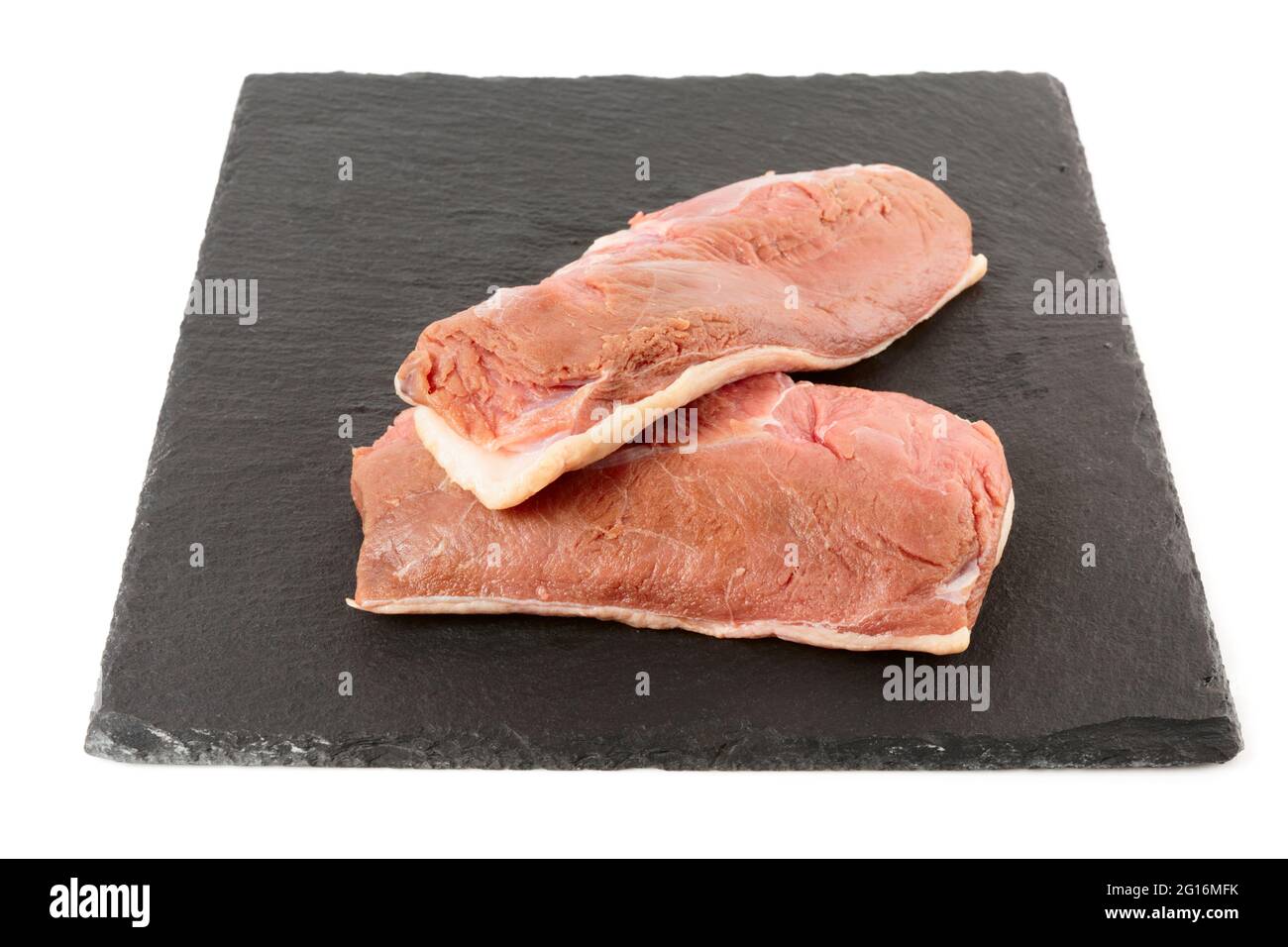 Two raw duck breast fillets on black slate plate, isolated on white background Stock Photo