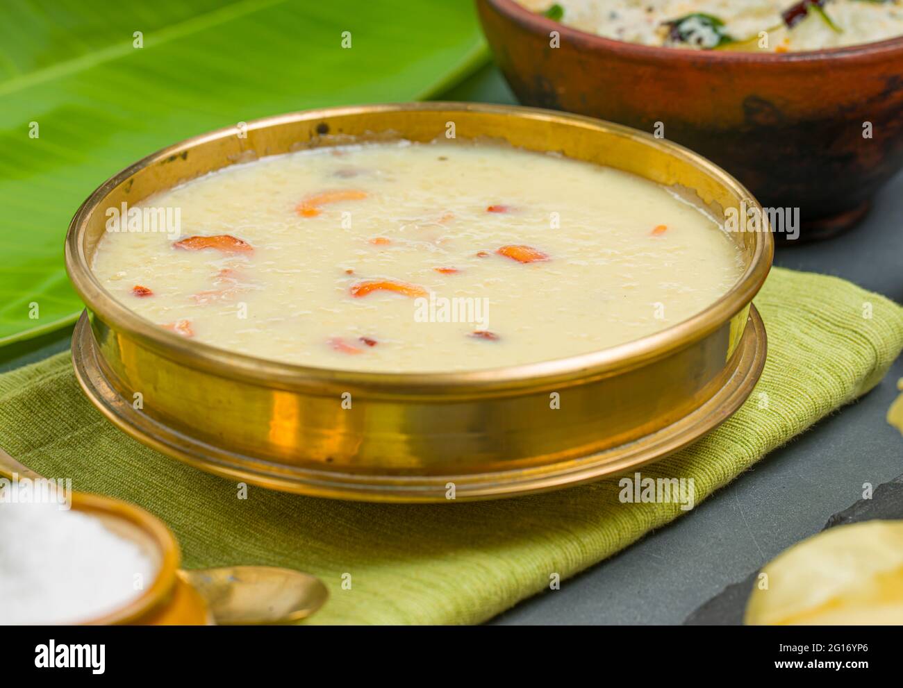Rice paalada payasam arranged in a brass vessel with Kerala feast side dishes in the background,selective focus. Stock Photo