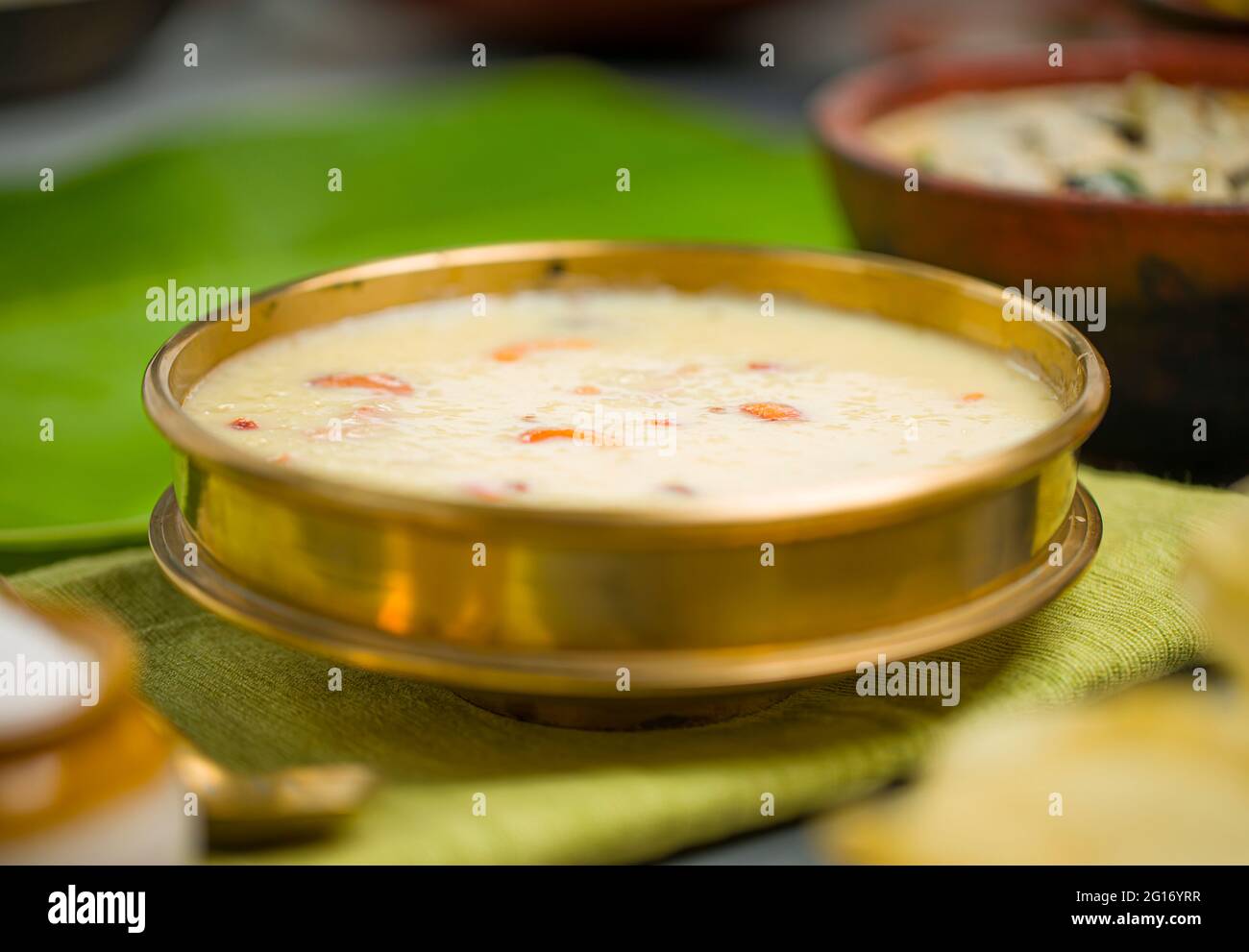Rice paalada payasam arranged in a brass vessel with Kerala feast side dishes in the background,selective focus. Stock Photo