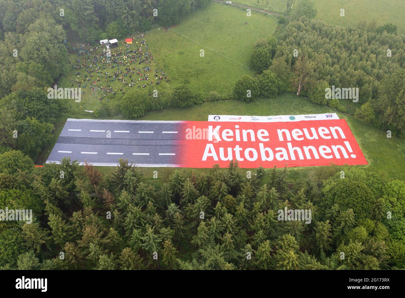 Rastede, Germany. 05th June, 2021. A banner with the inscription 'No new motorways!' representing a section of motorway can be seen on a land area. A protest against the planned construction of the A20 is taking place (shot with a drone). Credit: Mohssen Assanimoghaddam/dpa/Alamy Live News Stock Photo