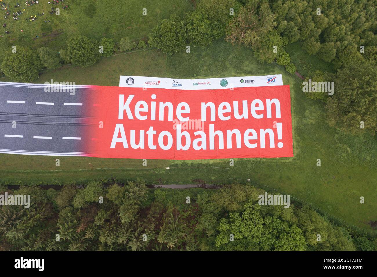Rastede, Germany. 05th June, 2021. A banner with the inscription 'No new motorways!' representing a section of motorway can be seen on a land area. A protest against the planned construction of the A20 is taking place (shot with a drone). Credit: Mohssen Assanimoghaddam/dpa/Alamy Live News Stock Photo
