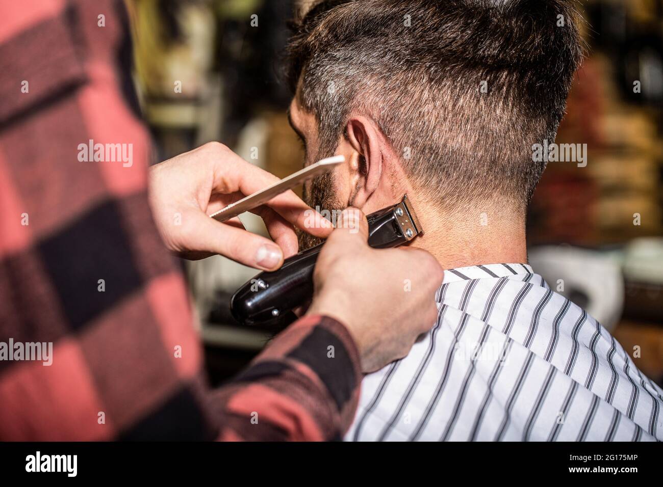 Man visiting hairstylist in Barber works with hair clipper