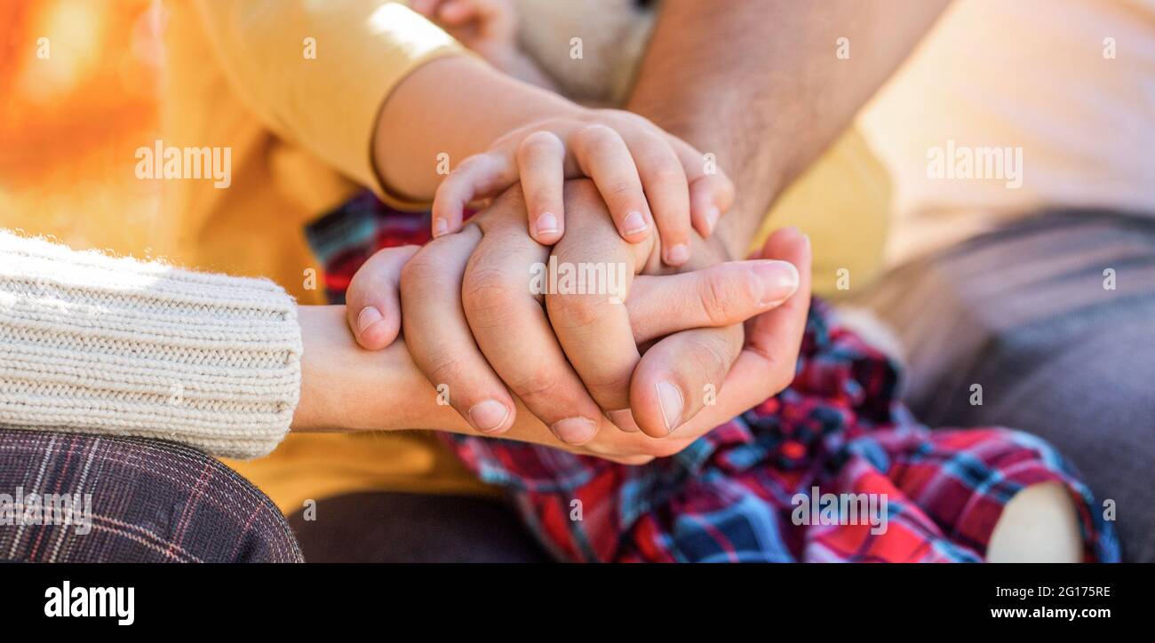 Parents hold the baby hands. Closeup of baby hand into parents hands. Concept of unity, support, protection, happiness. Child hand closeup into Stock Photo