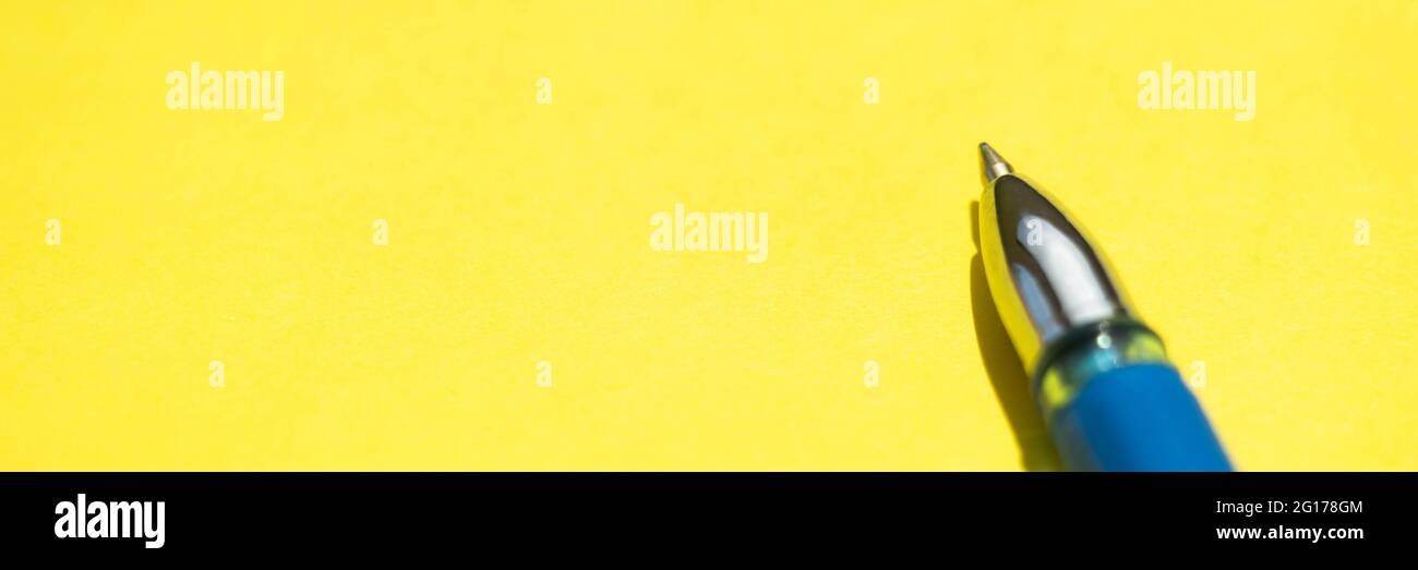 Blue ball pen closeup on a sunny yellow paper. Stock Photo