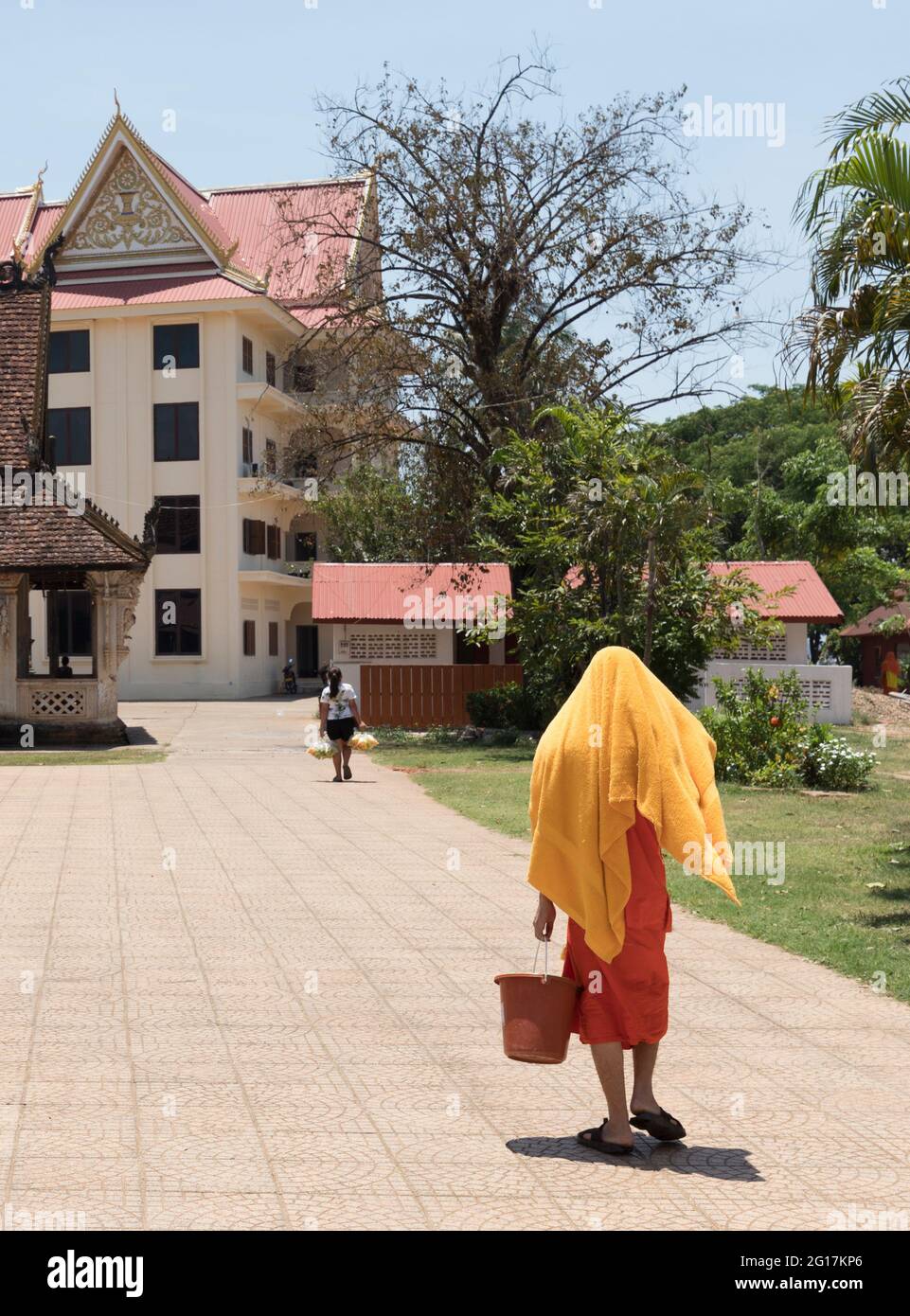 Buddhist moke walking with towel over head to keep the sun off, Wat Luang Pakse, temple in Pakse, Laos Stock Photo