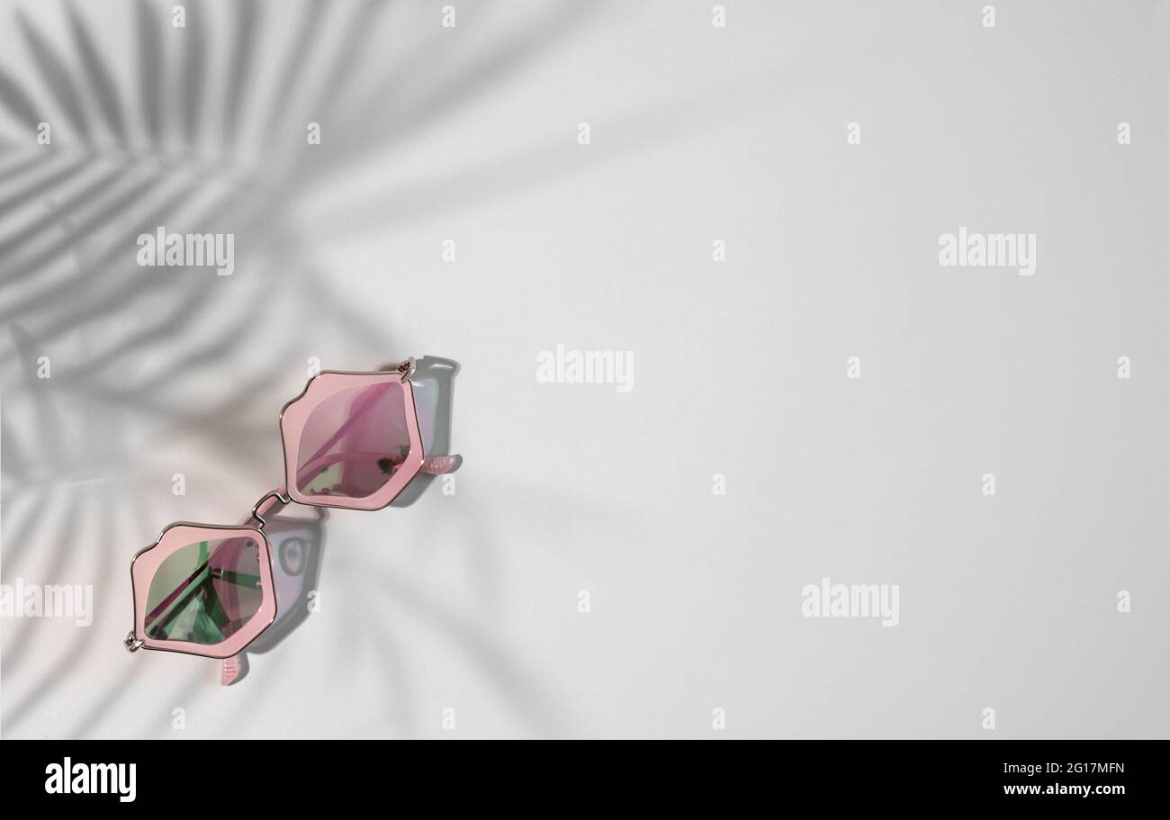 Funky sunglasses in pink lips shape on gray background with tropical shades and copy space Stock Photo