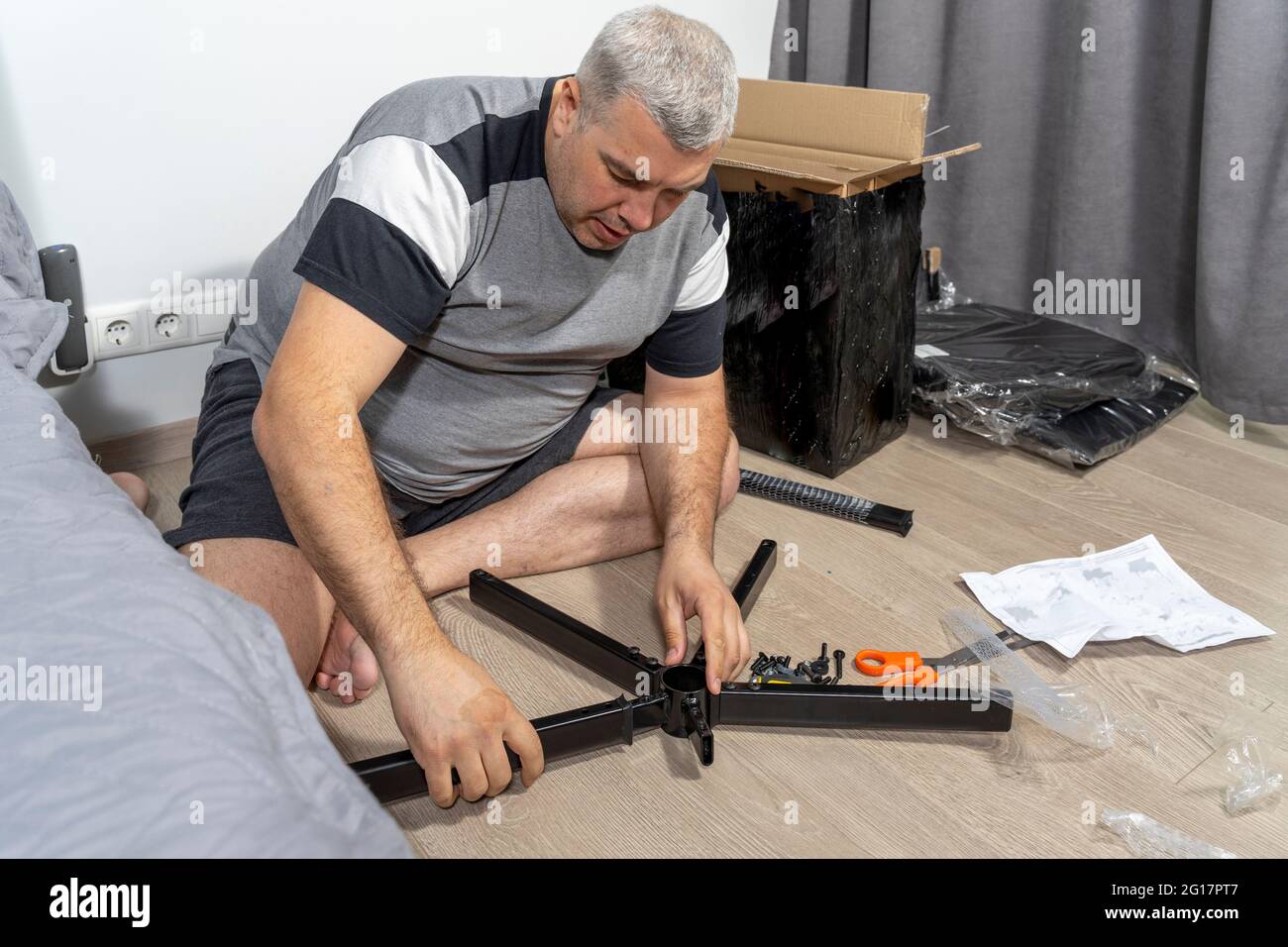 man assembles a chair according to instructions Stock Photo