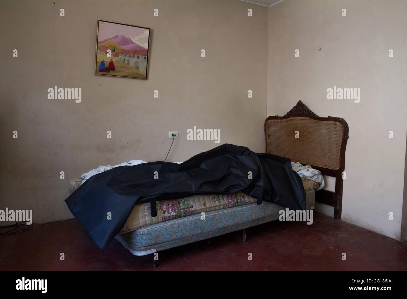 At the bedroom of María Jiménez Amado (65) there is a portrait of an Andean landscape that commands the empty walls. Beneath its flashy colors lays a black plastic bag containing her body. During 2021, 11% of all covid-19 deaths in Lima (Perú) occurred at home. According to the Peruvian government 185,380.00 people have died due to the coronavirus across the country. Peru. Stock Photo