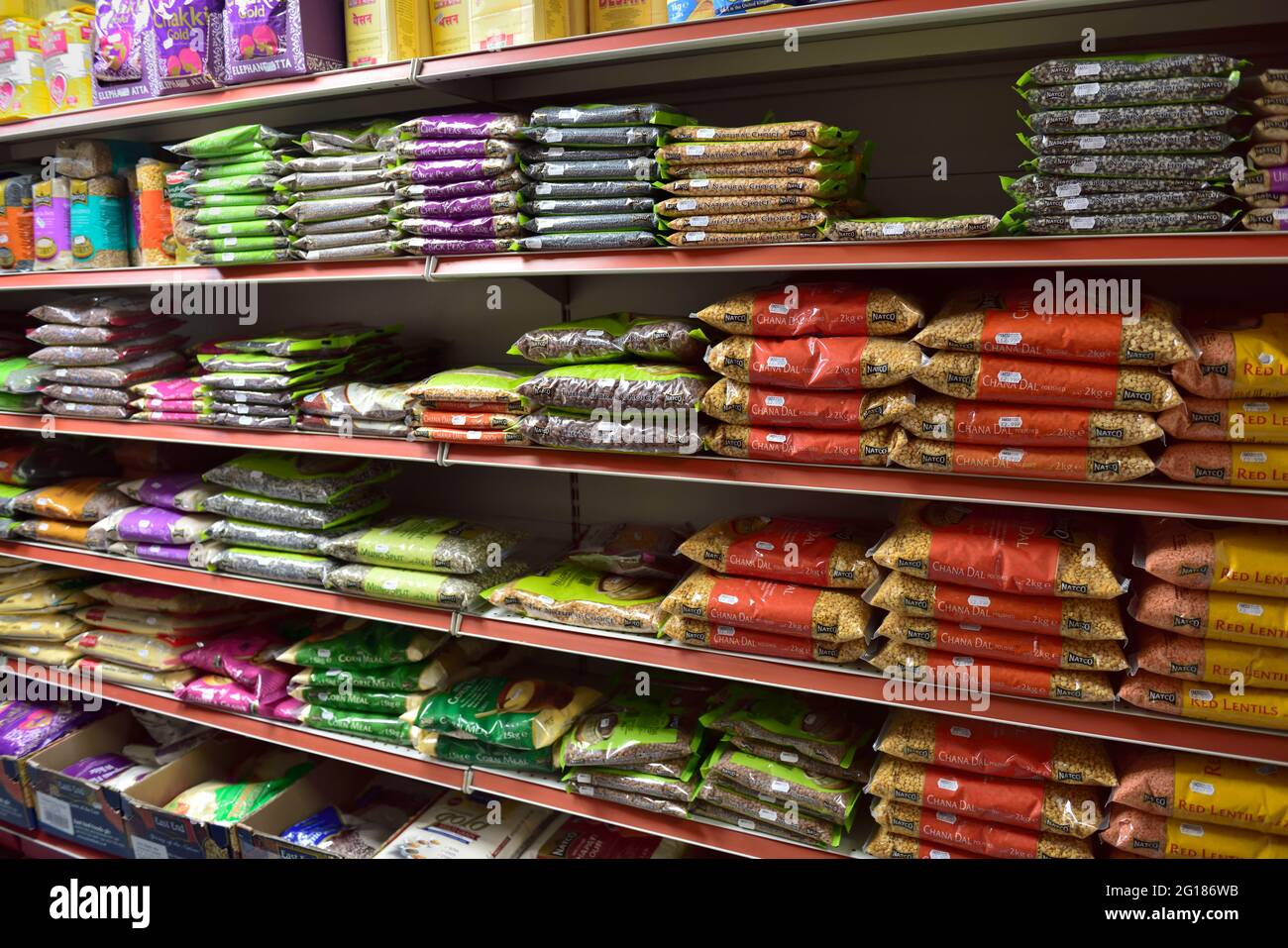 Shopper looking at bags of dried beans and lentils in small local well stocked corner grocery shop, UK Stock Photo